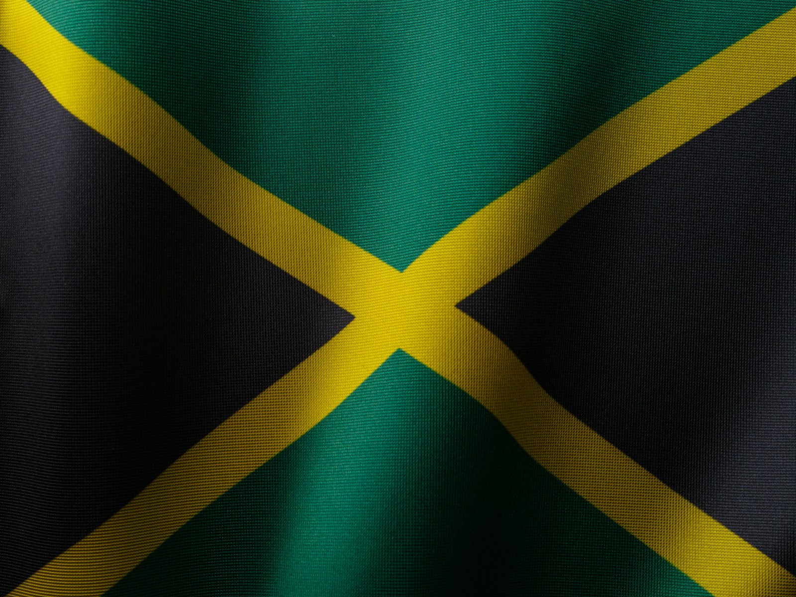 The Jamaican flag, black, green and gold, flying against a blue sky