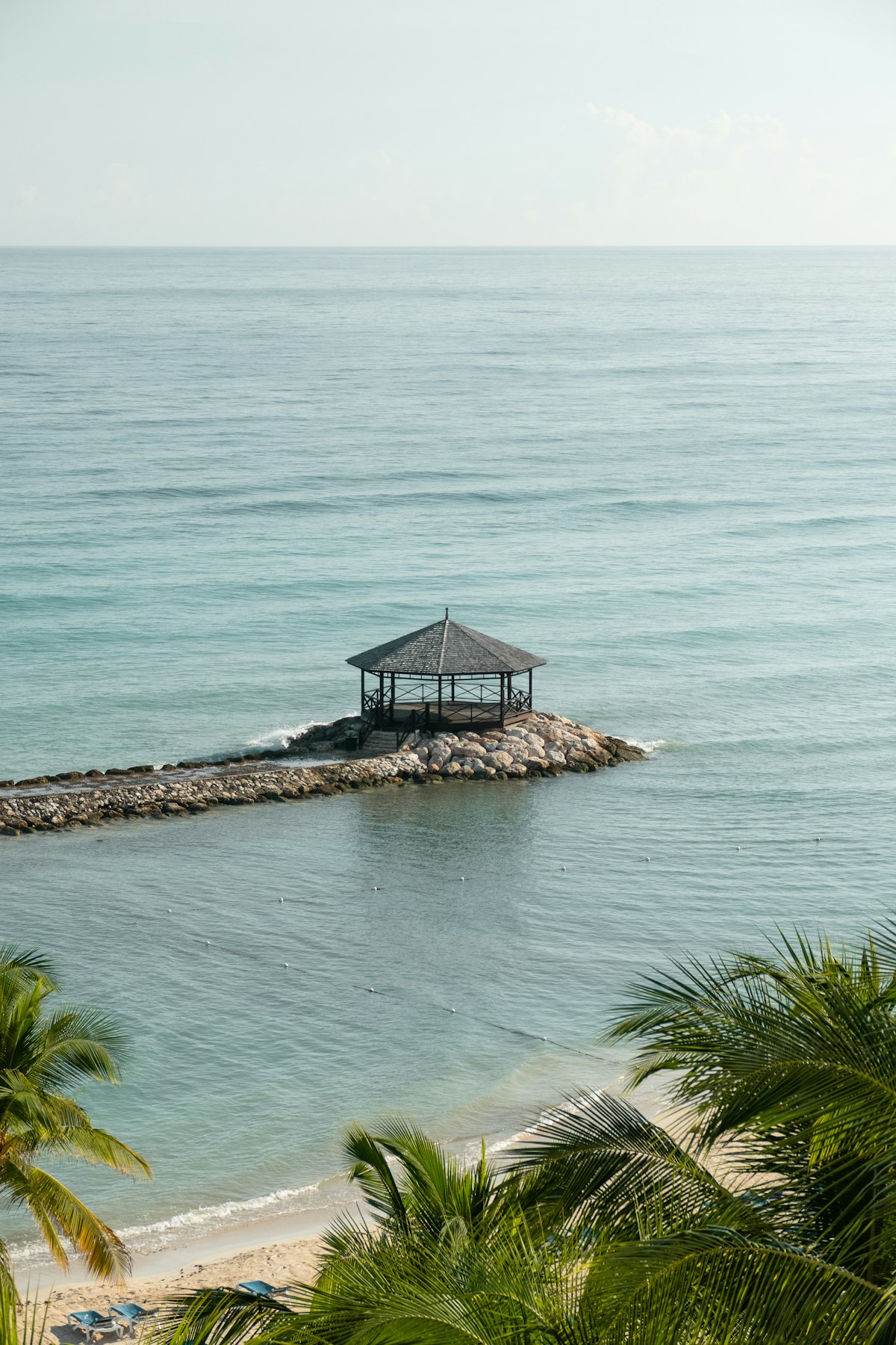 Wooden gazebo at the end of a rock jetty in calm turquoise sea off Montego Bay, Jamaica